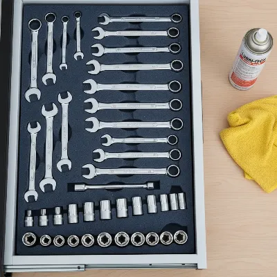 An open tool chest drawer with foam inserts and organized tools.